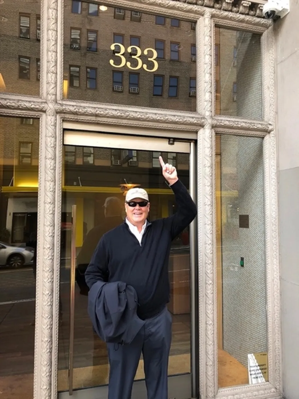 Jim smiling and pointing up at a gold 333 above the doorway of a building
