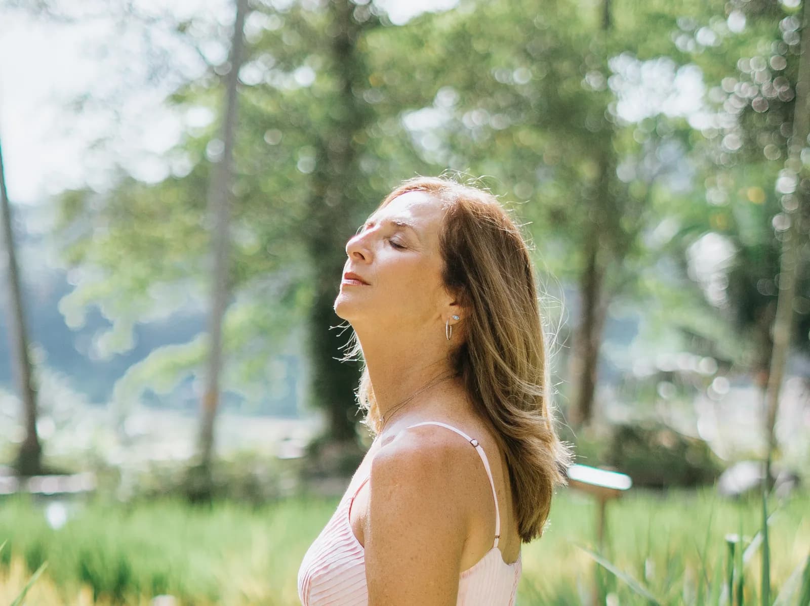 Julie Wright Halbert with her eyes closed and her head tilted back, among tall grass